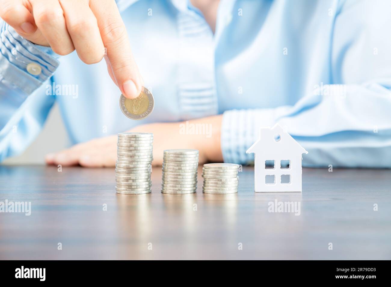 Mano che tiene monete di denaro per risparmiare per la casa residenziale. piano finanziario in contanti per prestiti o ipoteche e investimenti con banca. Concetto per assicuratore della casa Foto Stock