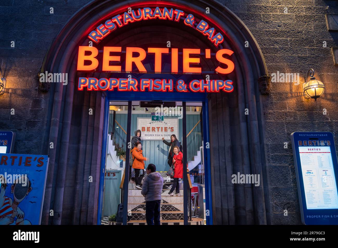 Edimburgo, Scozia, Bertie's propriamente Ristorante e Bar con Fish and Chips di notte, con i turisti asiatici in posa per una foto all'ingresso, situato sulla V Foto Stock