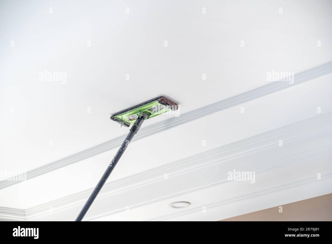 Il padrone levigare l'intonaco sul soffitto della stanza da verniciare Foto Stock