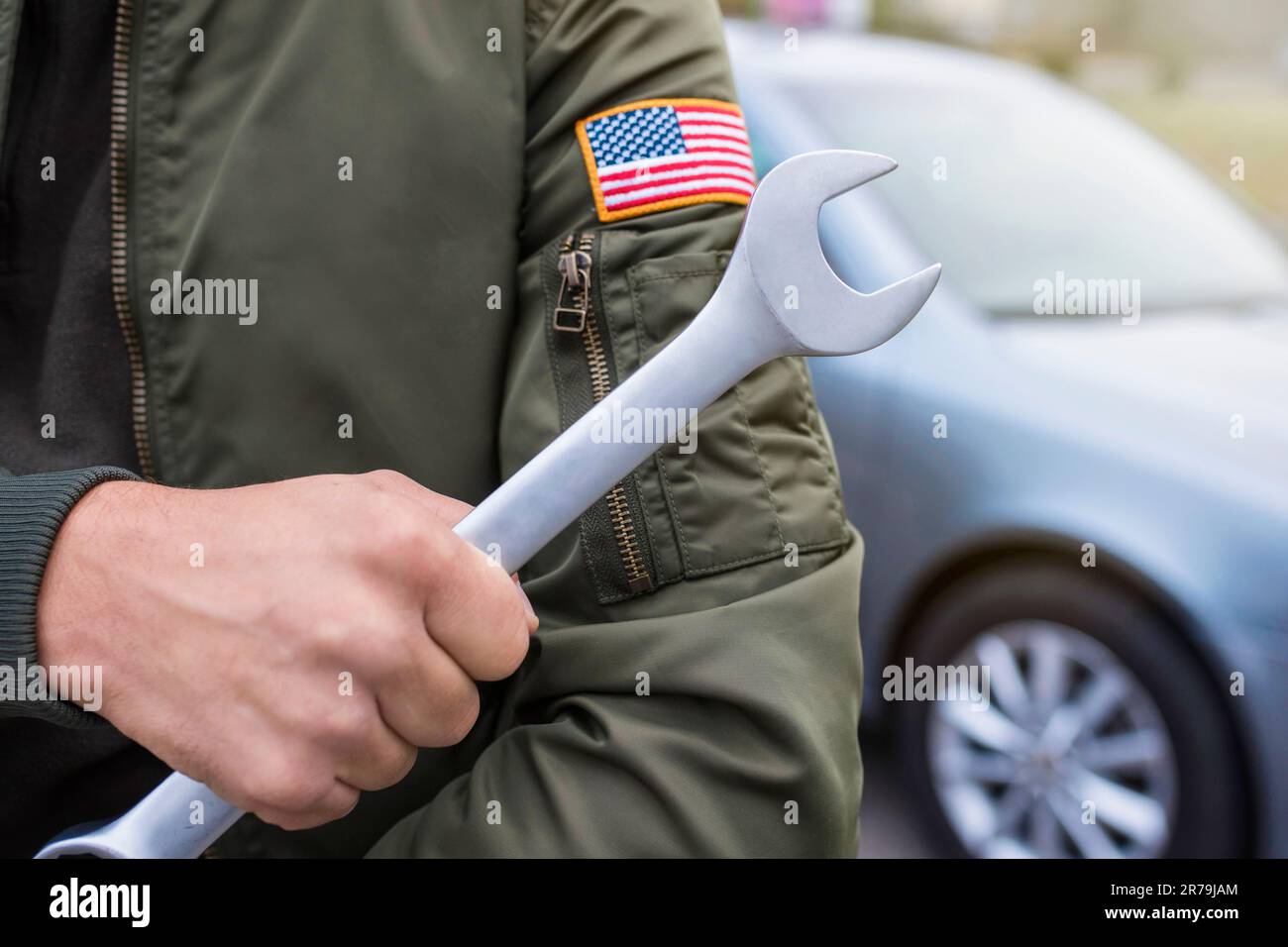 Il meccanico dell'automobile tiene una chiave sul fondo dell'automobile. Concetto di riparazione automatica, stile di vita Foto Stock