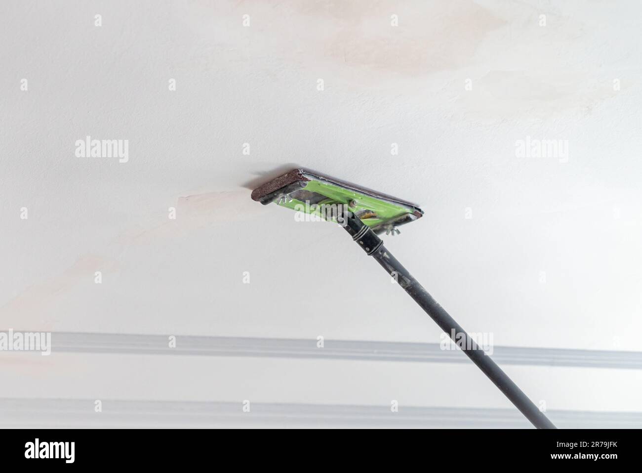 Il padrone levigare l'intonaco sul soffitto della stanza da verniciare Foto Stock