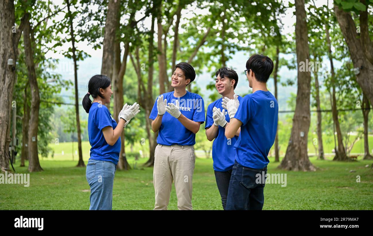 Un gruppo di giovani e allegri volontari asiatici si sono scontrati con le mani per celebrare il loro evento benefico di successo nel parco. Progetto CSR, comunità di supporto, car Foto Stock