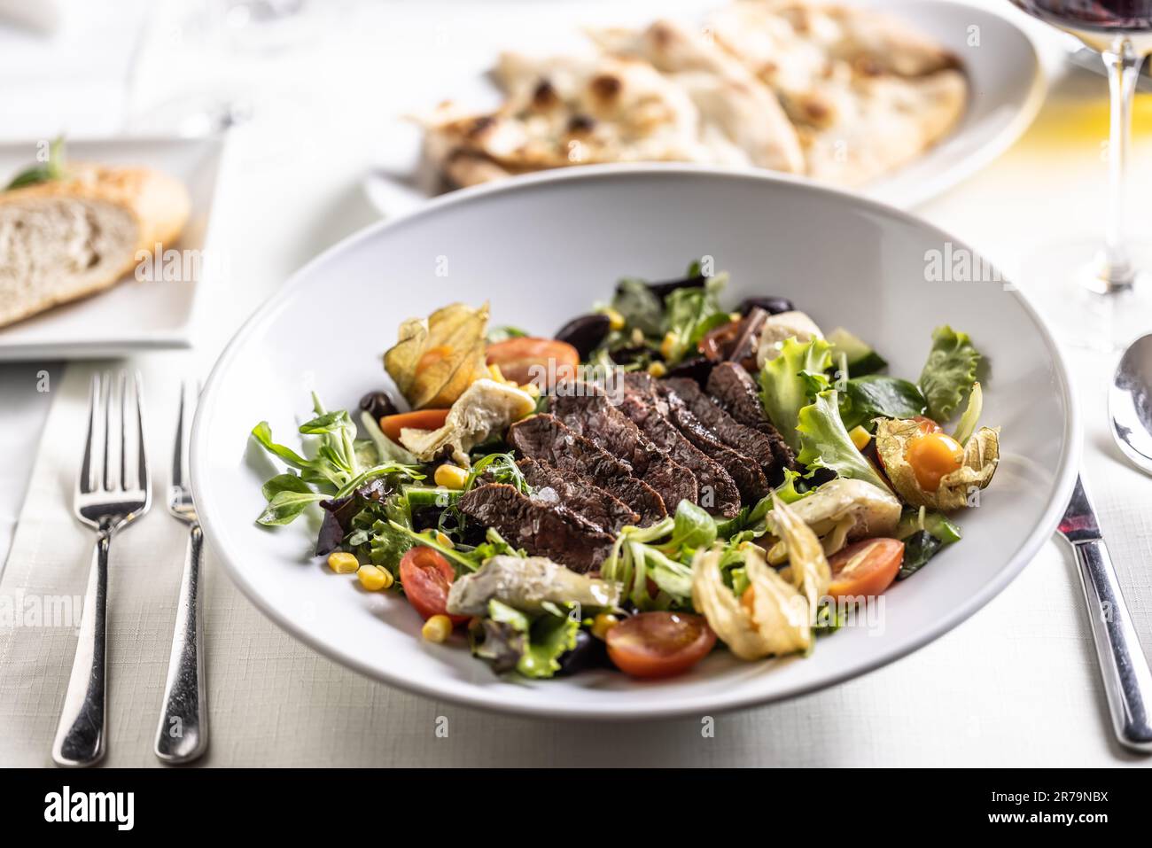Insalata mista colorata con fette di bistecca poste sopra di essa. Foto Stock