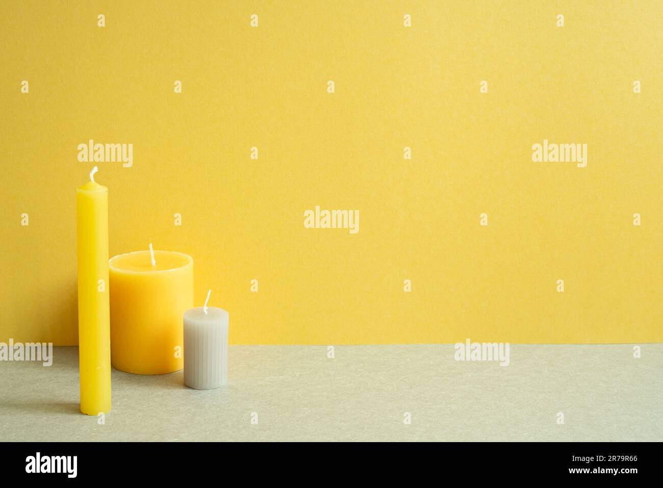 Candela minima sul tavolo grigio. sfondo giallo parete Foto Stock