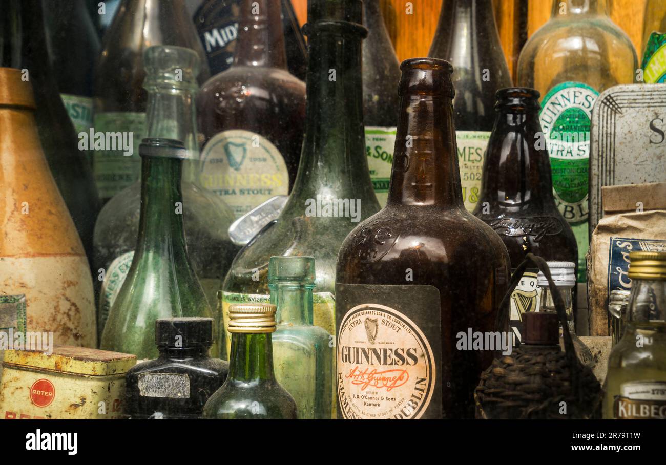 Bottiglie vecchie e polverose nell'espositore esterno di un pub irlandese, collezione di bottiglie di birra guinness, profondità di campo poco profonda. Foto Stock