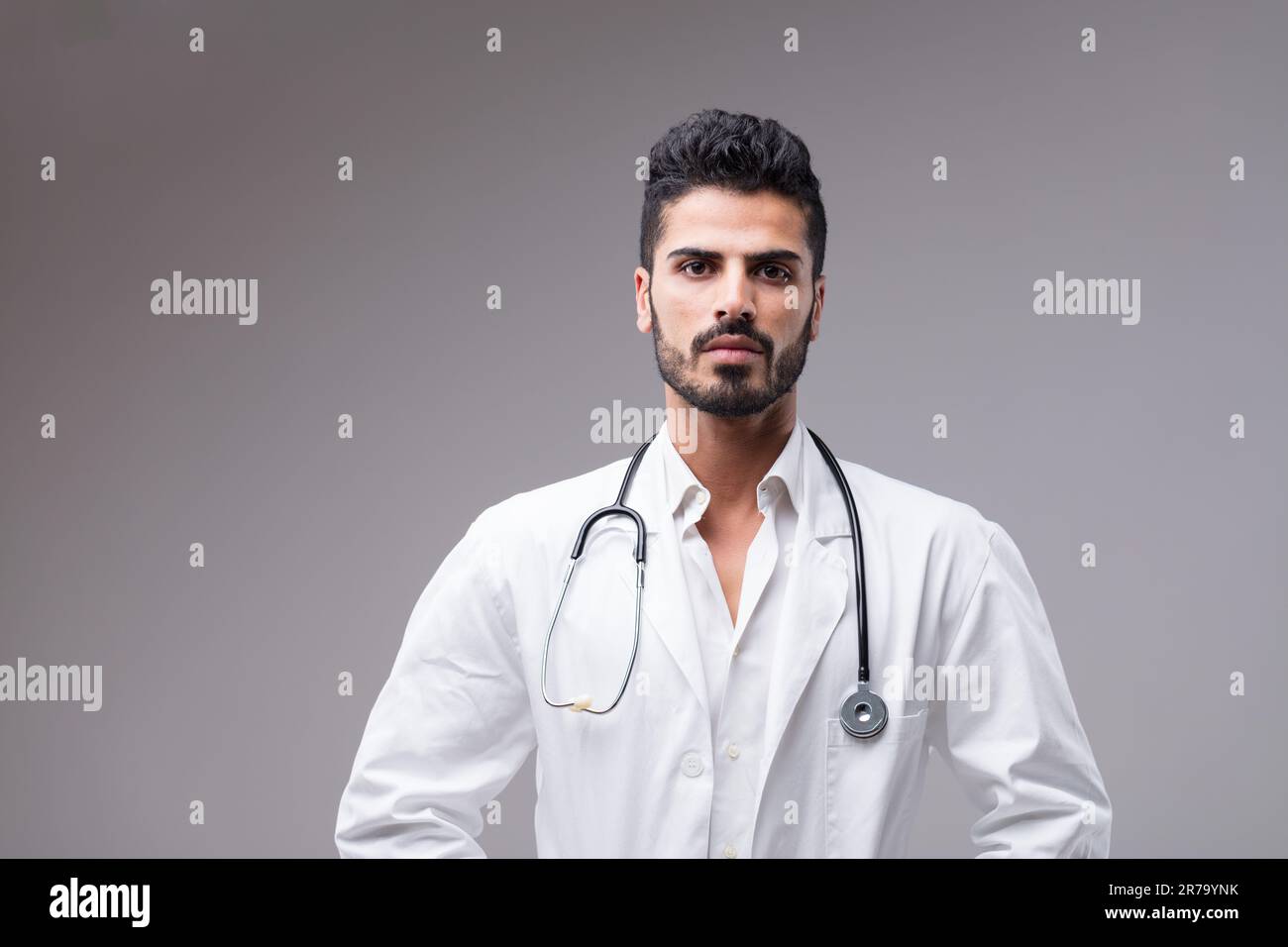 Un medico serio, mediorientale con una carnagione scura. Ritratto di un giovane uomo, barba curata professionalmente, pronto ad assisterti Foto Stock