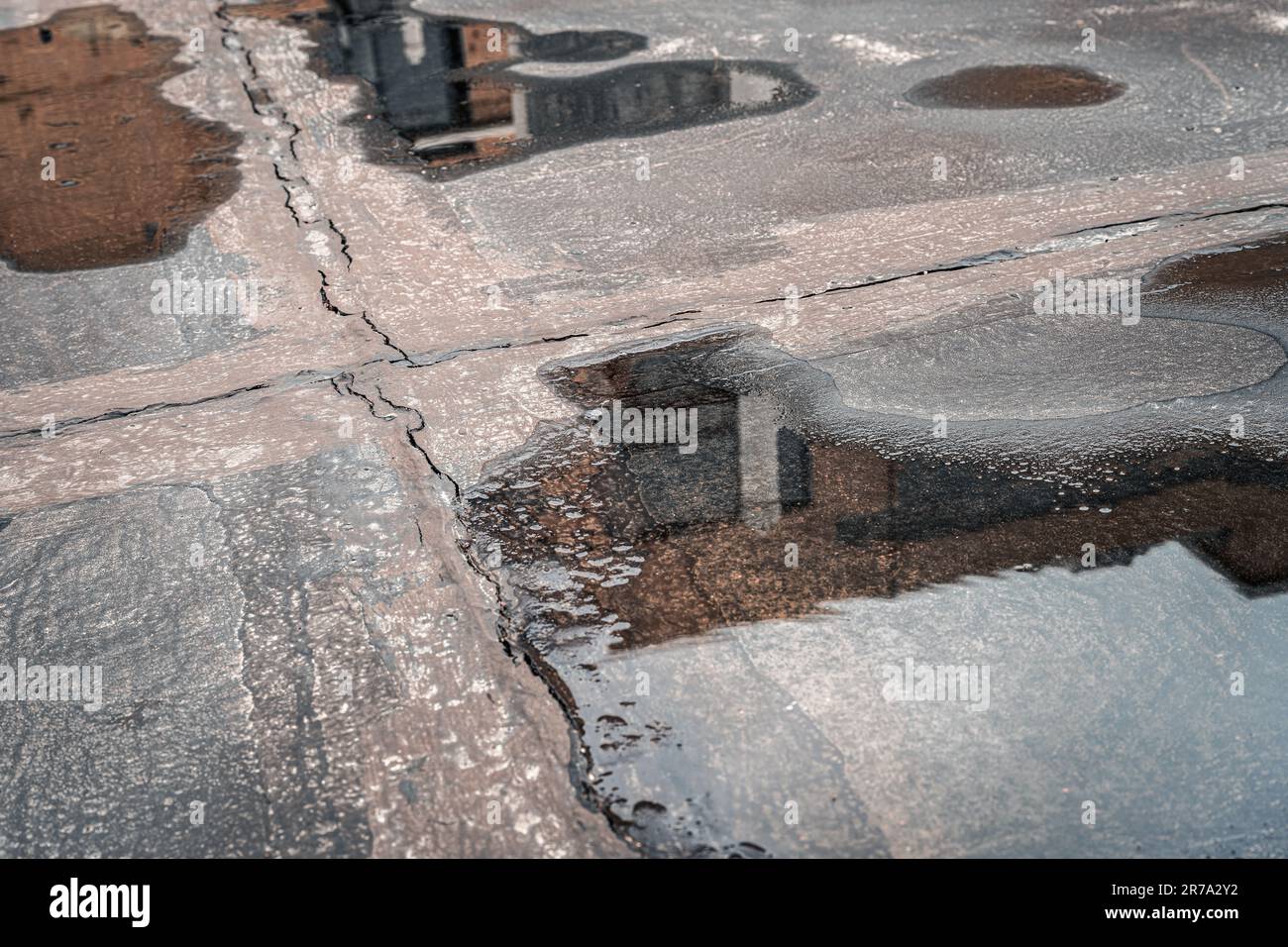 Pudddles sulla superficie della strada in una giornata piovosa. Foto Stock