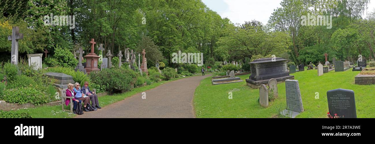 I visitatori si siedono e riposano accanto alle tombe lungo un sentiero nel cimitero di Highgate, uno storico cimitero vittoriano a nord di Londra, Inghilterra, Regno Unito Foto Stock