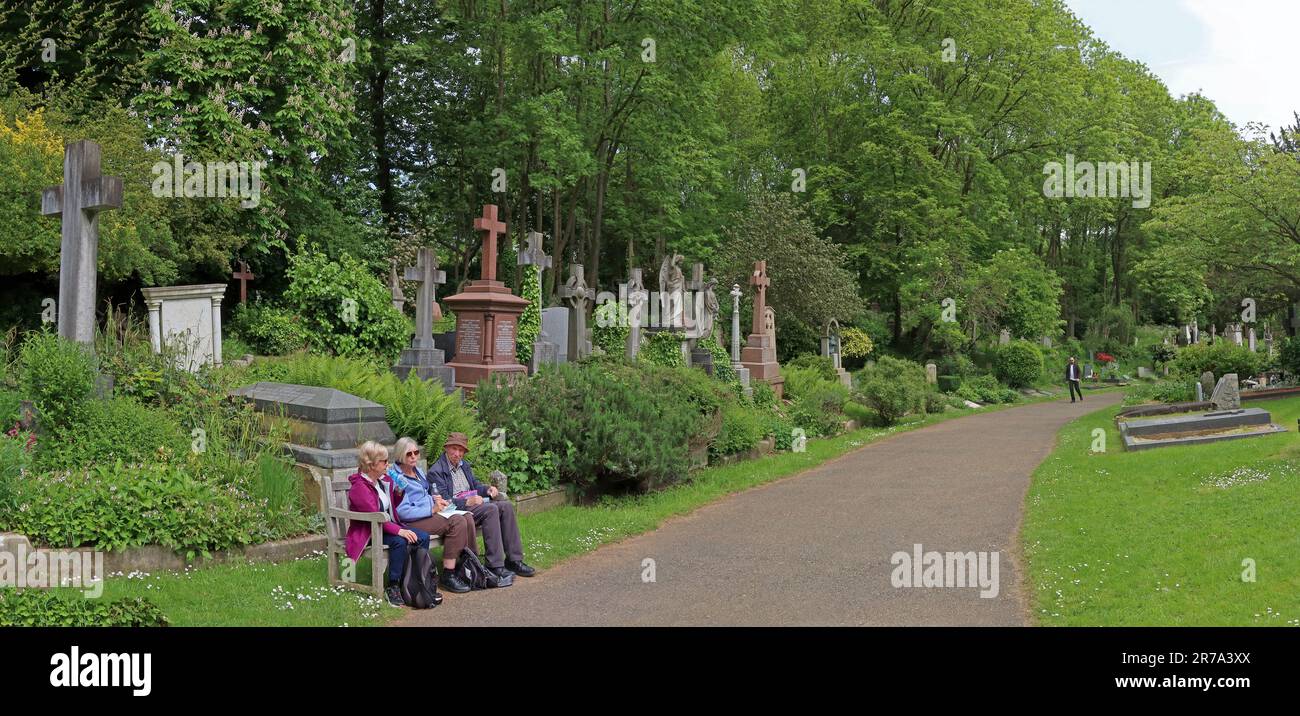 I visitatori si siedono e riposano accanto alle tombe lungo un sentiero nel cimitero di Highgate, uno storico cimitero vittoriano a nord di Londra, Inghilterra, Regno Unito Foto Stock
