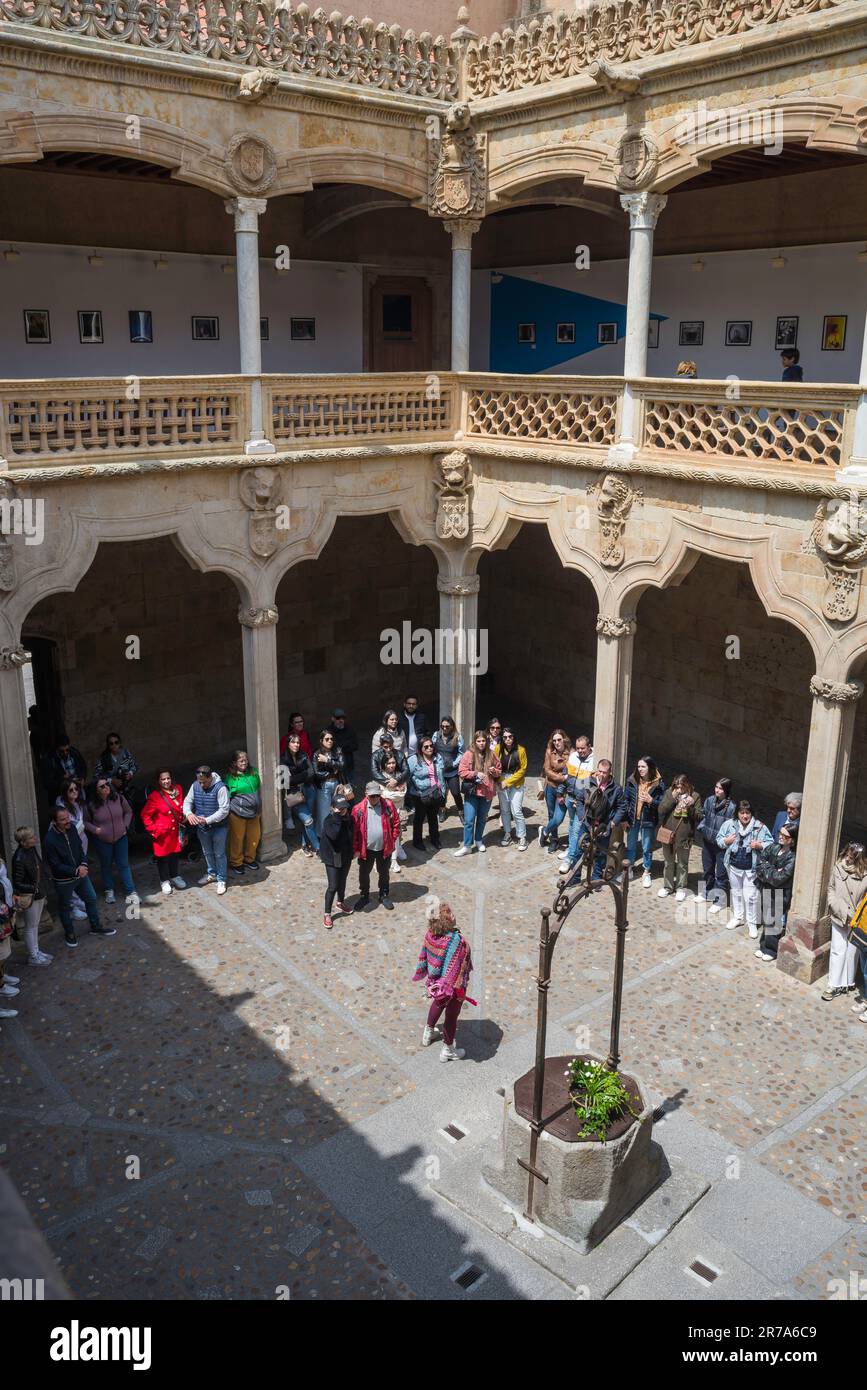 Tour di gruppo in Europa, guarda i turisti in estate ascoltando la loro guida turistica nel cortile patio della Casa de las Conchas a Salamanca, Spagna Foto Stock