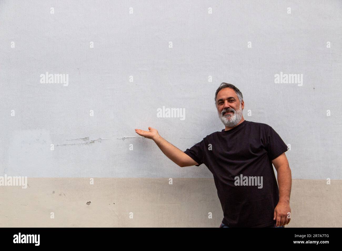 Uomo adulto con barba e ventre, t-shirt nera che punta allo spazio delle copie Foto Stock