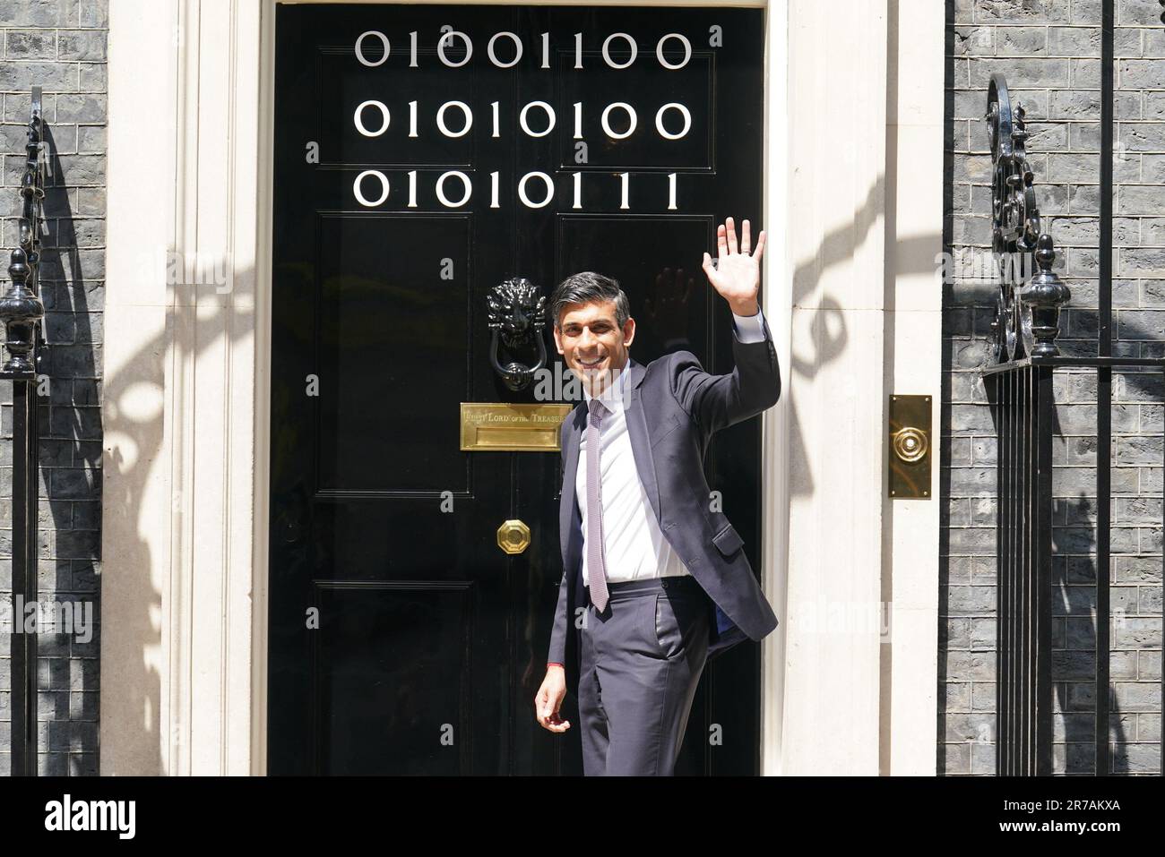 Il primo ministro Rishi Sunak si trova all'ingresso di 10 Downing Street, Londra, mentre i numeri attaccati alla porta spiegano la "London Tech Week" in codice binario, davanti a un ricevimento in giardino per la London Tech Week. Il codice binario è una forma di linguaggio di codifica che utilizza solo due simboli, '0' e '1', per trasmettere e memorizzare le informazioni. Data immagine: Mercoledì 14 giugno 2023. Foto Stock