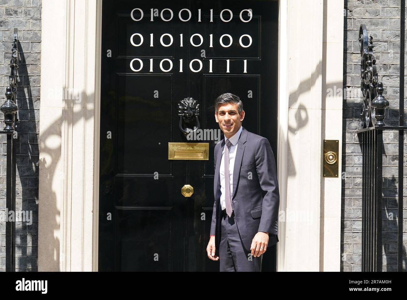 Il primo ministro Rishi Sunak si trova all'ingresso di 10 Downing Street, Londra, mentre i numeri attaccati alla porta spiegano la "London Tech Week" in codice binario, davanti a un ricevimento in giardino per la London Tech Week. Il codice binario è una forma di linguaggio di codifica che utilizza solo due simboli, '0' e '1', per trasmettere e memorizzare le informazioni. Data immagine: Mercoledì 14 giugno 2023. Foto Stock