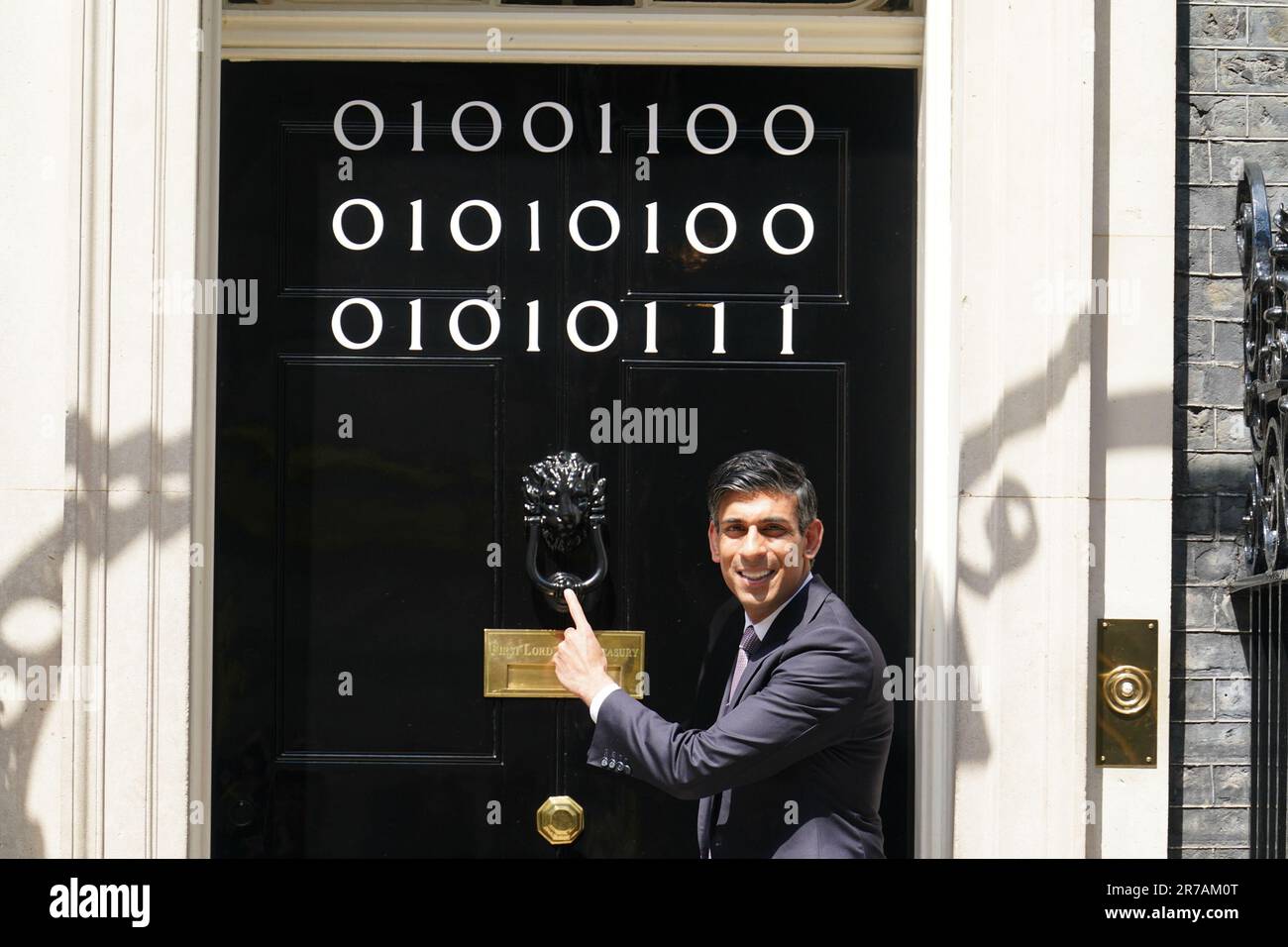 Il primo ministro Rishi Sunak si trova all'ingresso di 10 Downing Street, Londra, mentre i numeri attaccati alla porta spiegano la "London Tech Week" in codice binario, davanti a un ricevimento in giardino per la London Tech Week. Il codice binario è una forma di linguaggio di codifica che utilizza solo due simboli, '0' e '1', per trasmettere e memorizzare le informazioni. Data immagine: Mercoledì 14 giugno 2023. Foto Stock