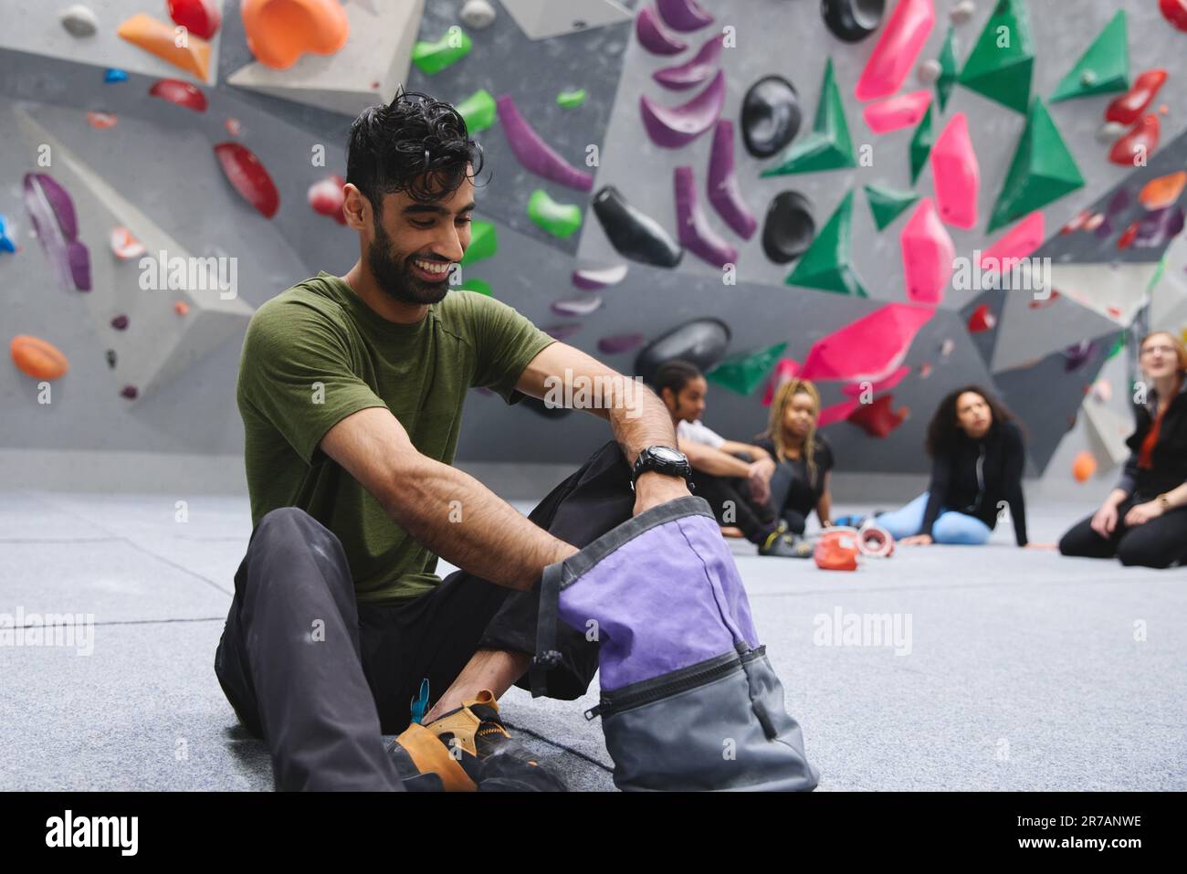 Uomo che si strofina le mani con gesso pronto per l'arrampicata al muro al centro interno Foto Stock