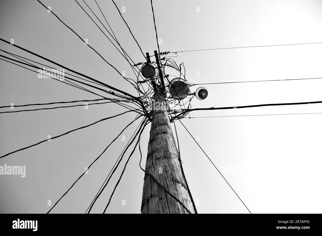 Un polo in legno per la linea elettrica ad alta tensione in scala di grigi Foto Stock
