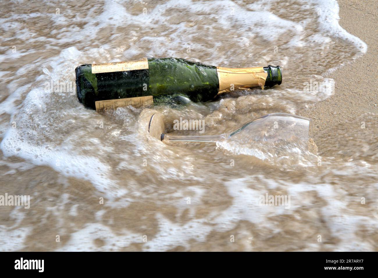 Onde del mare sabbia marrone champagne bottiglia vino bicchiere vuoto Foto Stock