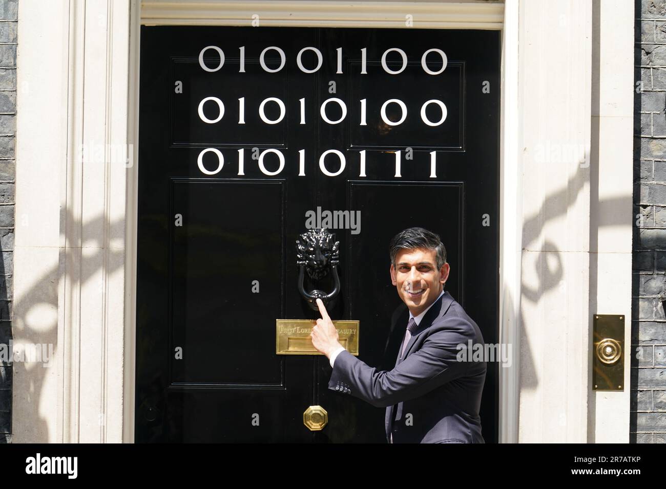 Il primo ministro Rishi Sunak si trova all'ingresso di 10 Downing Street, Londra, mentre i numeri attaccati alla porta spiegano la "London Tech Week" in codice binario, davanti a un ricevimento in giardino per la London Tech Week. Il codice binario è una forma di linguaggio di codifica che utilizza solo due simboli, '0' e '1', per trasmettere e memorizzare le informazioni. Data immagine: Mercoledì 14 giugno 2023. Foto Stock