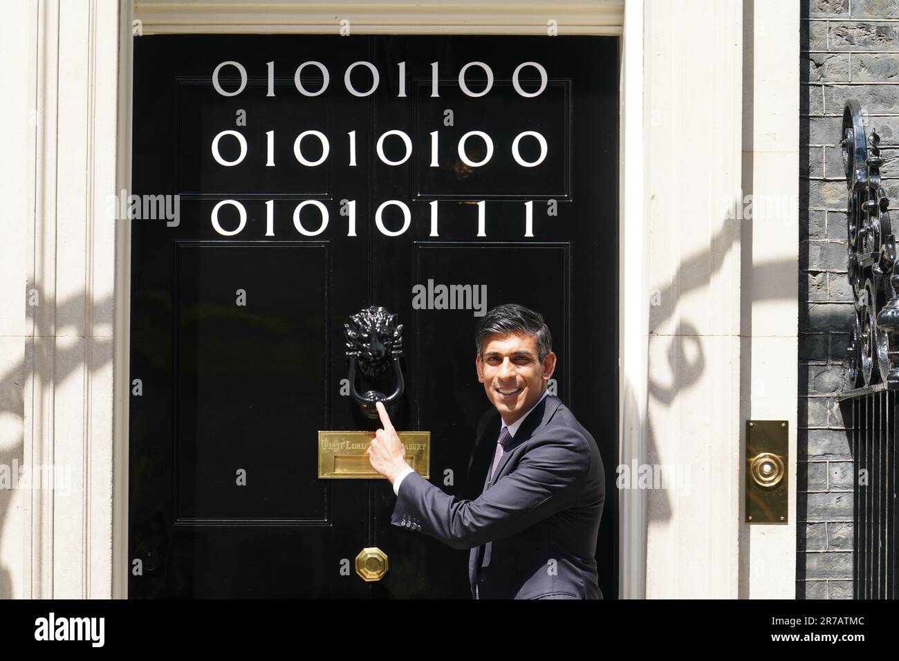 Il primo ministro Rishi Sunak si trova all'ingresso di 10 Downing Street, Londra, mentre i numeri attaccati alla porta spiegano la "London Tech Week" in codice binario, davanti a un ricevimento in giardino per la London Tech Week. Il codice binario è una forma di linguaggio di codifica che utilizza solo due simboli, '0' e '1', per trasmettere e memorizzare le informazioni. Data immagine: Mercoledì 14 giugno 2023. Foto Stock