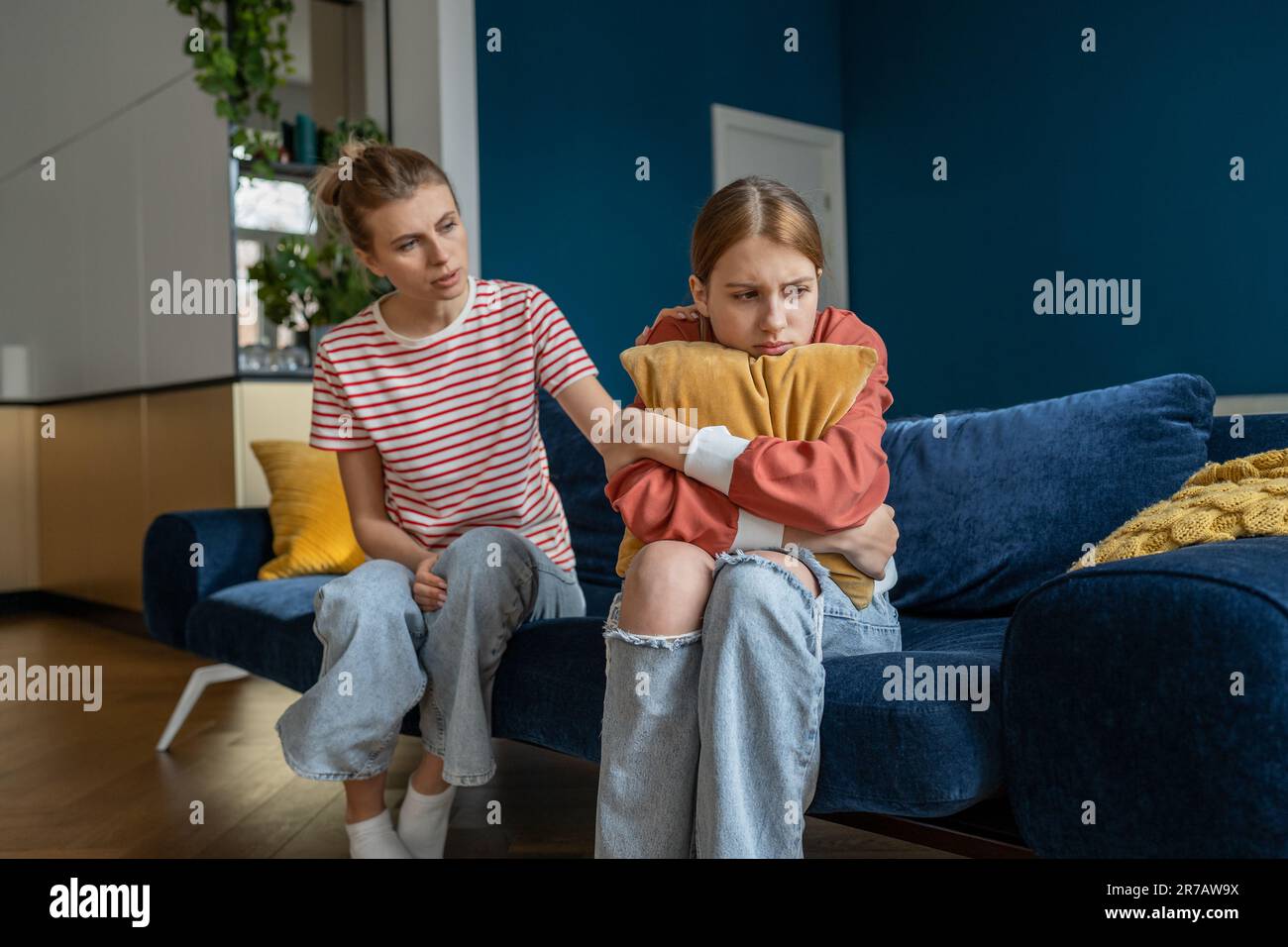 la mamma affettuosa sta cercando di stabilire un contatto con la figlia adolescente seduta sul divano a casa. Foto Stock