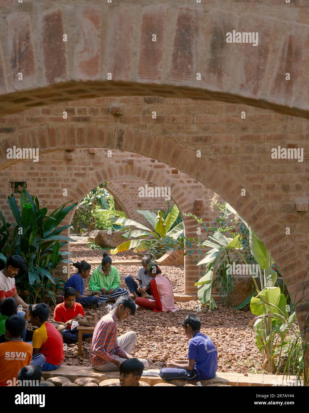 Guarda attraverso gli archi con i bambini in un laboratorio d'arte. Rovine subteraniche, Kaggalipura, Bangalore, India. Architetto: A Threshold Architects, 2023. Foto Stock