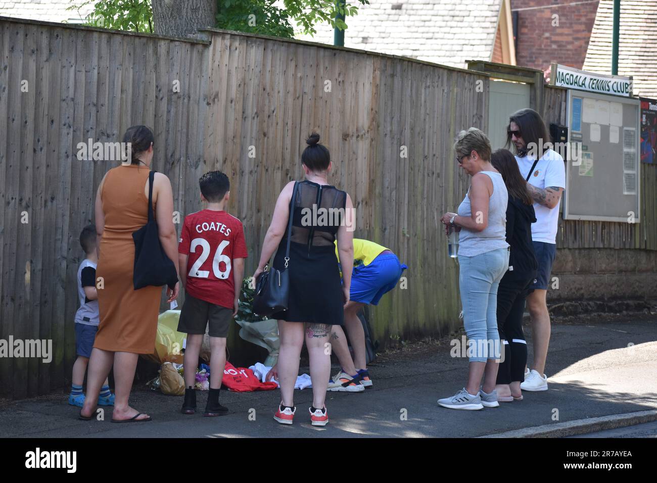 Lee Coates (centro in alto giallo) e James Coates (bianco in alto a destra) i figli del custode della scuola Ian Coates, visitare la scena con altri membri della famiglia per porre i fiori e posizionare le cime del calcio sul marciapiede in Magdala Road, Nottingham, dove il 65-year-old è stato trovato pugnalato. Tre persone sono state uccise e altre tre ferite in attacchi connessi il martedì mattina. Data immagine: Mercoledì 14 giugno 2023. Foto Stock