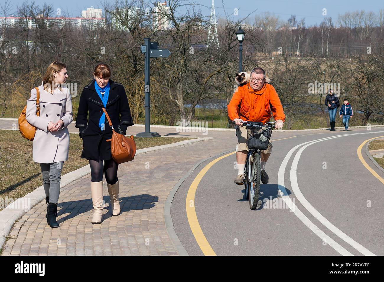 Minsk, Bielorussia - 23 marzo 2014: Un uomo con un gatto sulle sue spalle cavalca una bicicletta. Animali domestici sulla passeggiata originale Foto Stock