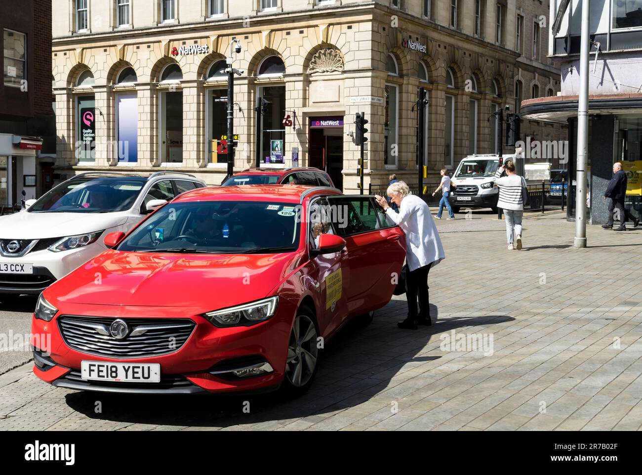 Taxi che scende da Eldrly Lady High Street, Lincoln City, Lincolnshire, Inghilterra, Regno Unito Foto Stock