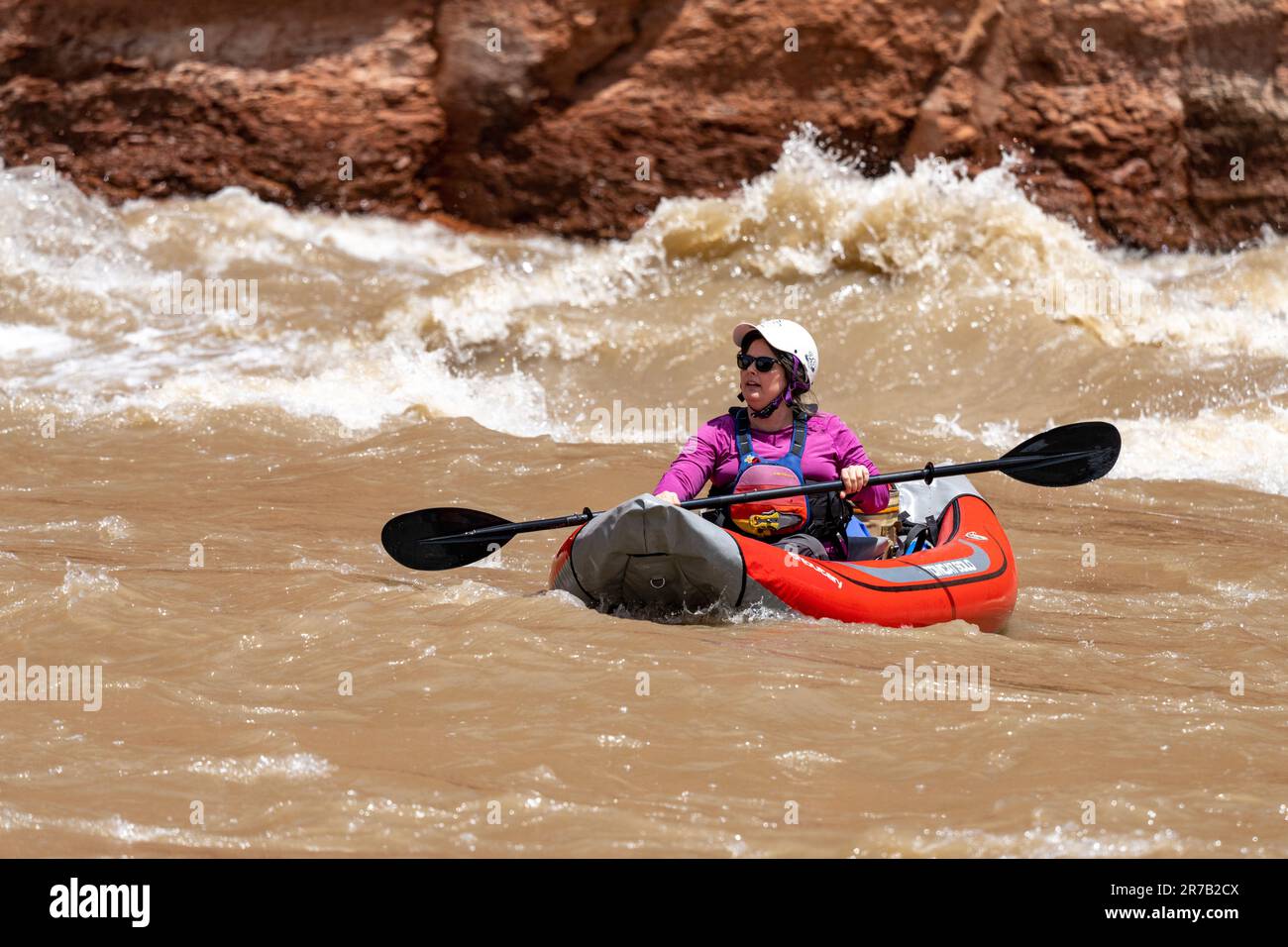 Una donna corre White's Rapid sul fiume Colorado in acqua alta in un kayak gonfiabile o un duckie. Moab, Utah. Foto Stock