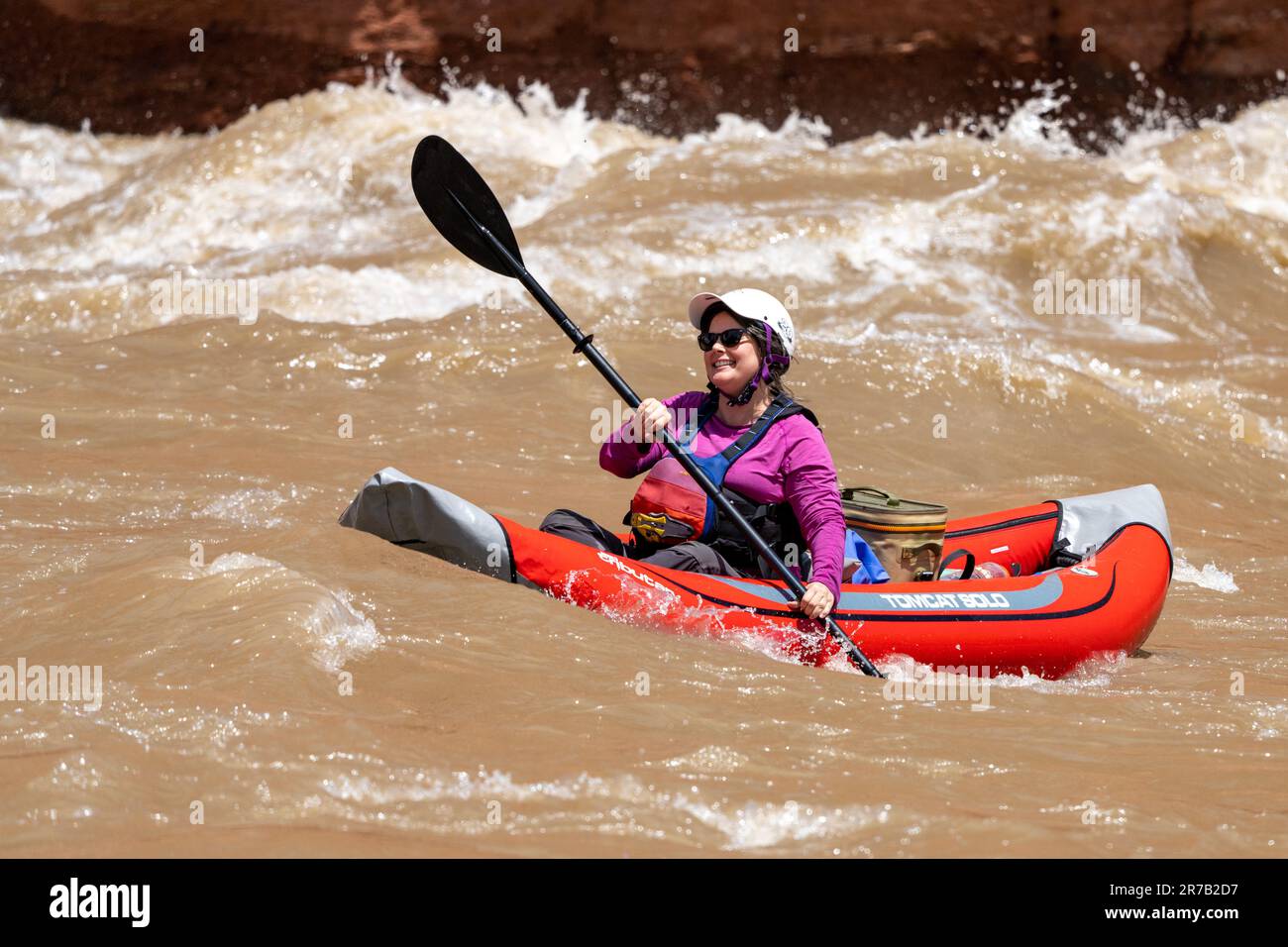 Una donna corre White's Rapid sul fiume Colorado in acqua alta in un kayak gonfiabile o un duckie. Moab, Utah. Foto Stock