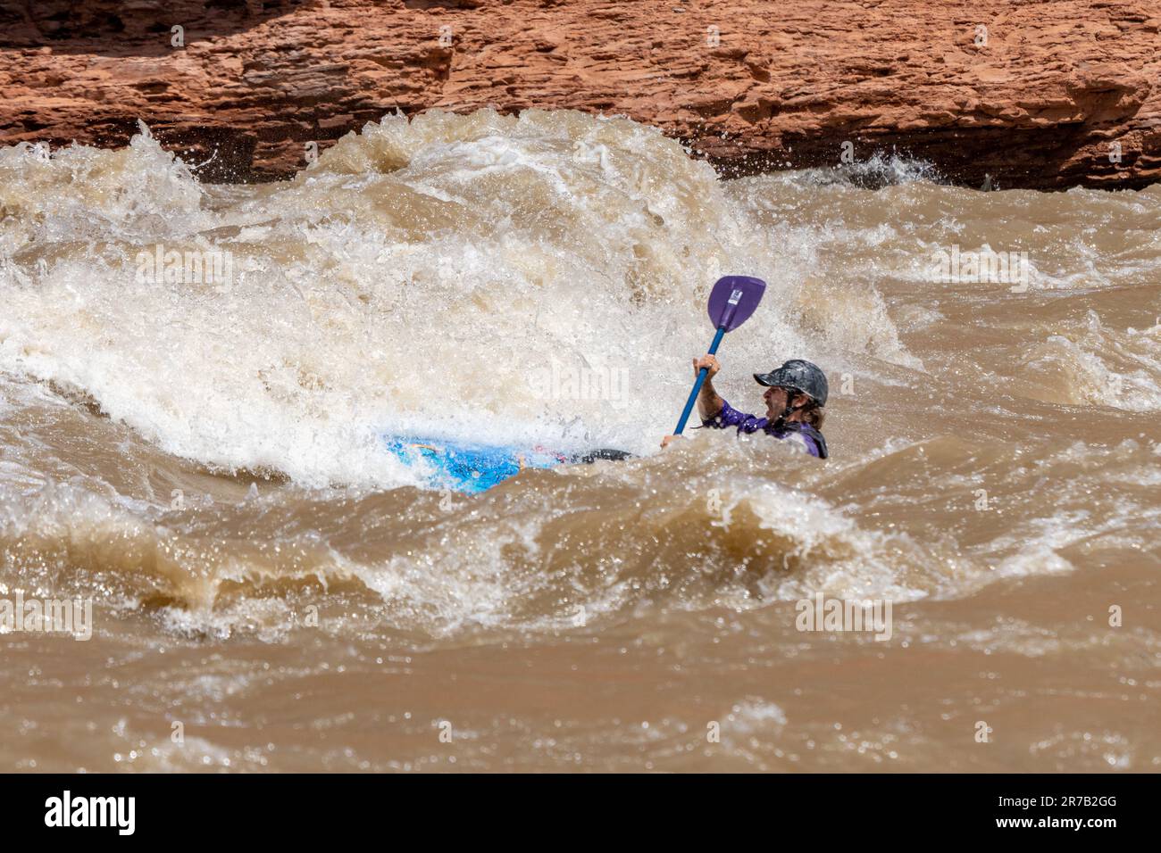 Un kayaker negozia grandi onde a White's Rapid sul fiume Colorado ad alta quota. Moab, Utah. Foto Stock