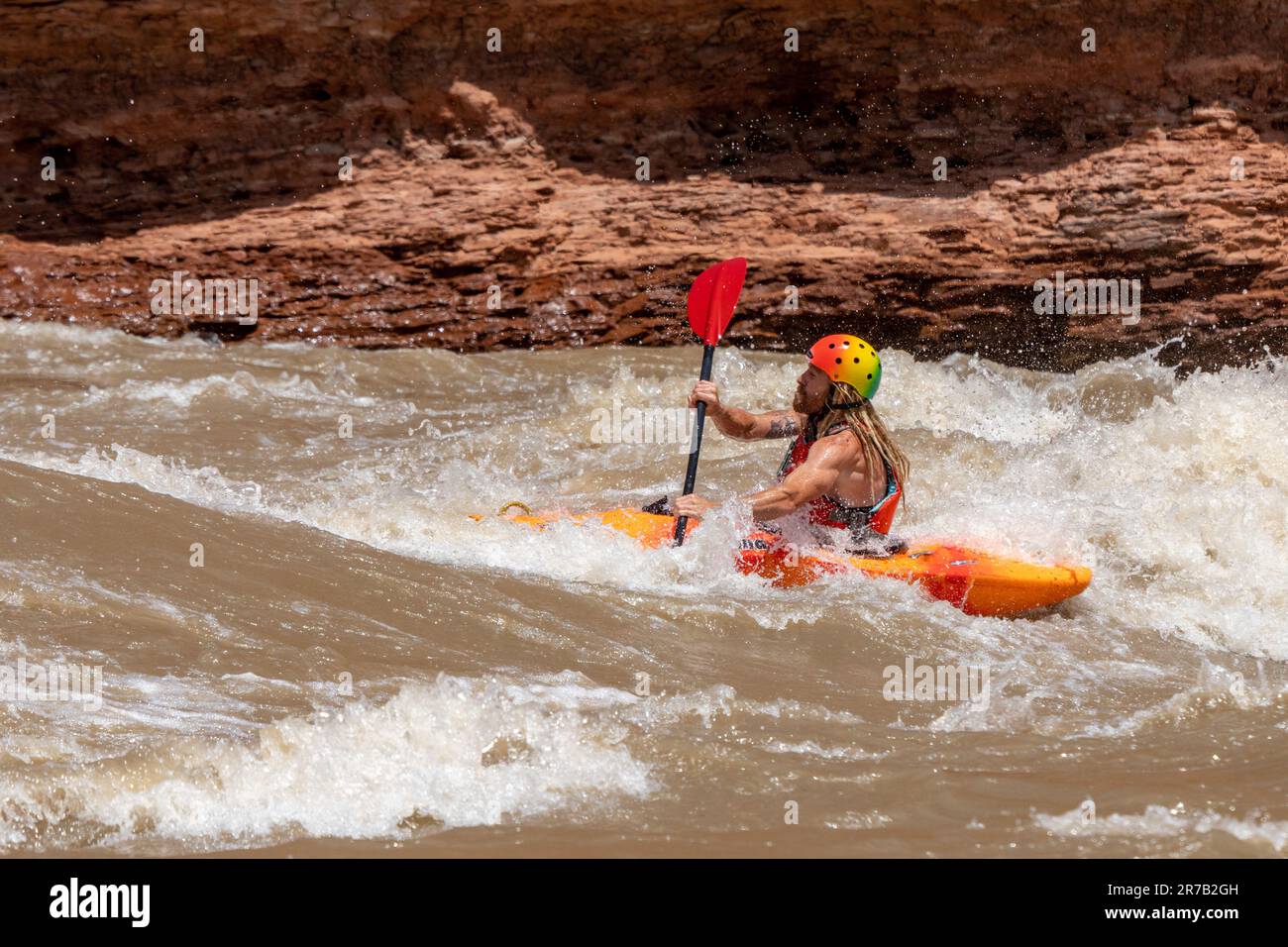 Un kayaker negozia grandi onde a White's Rapid sul fiume Colorado ad alta quota. Moab, Utah. Foto Stock