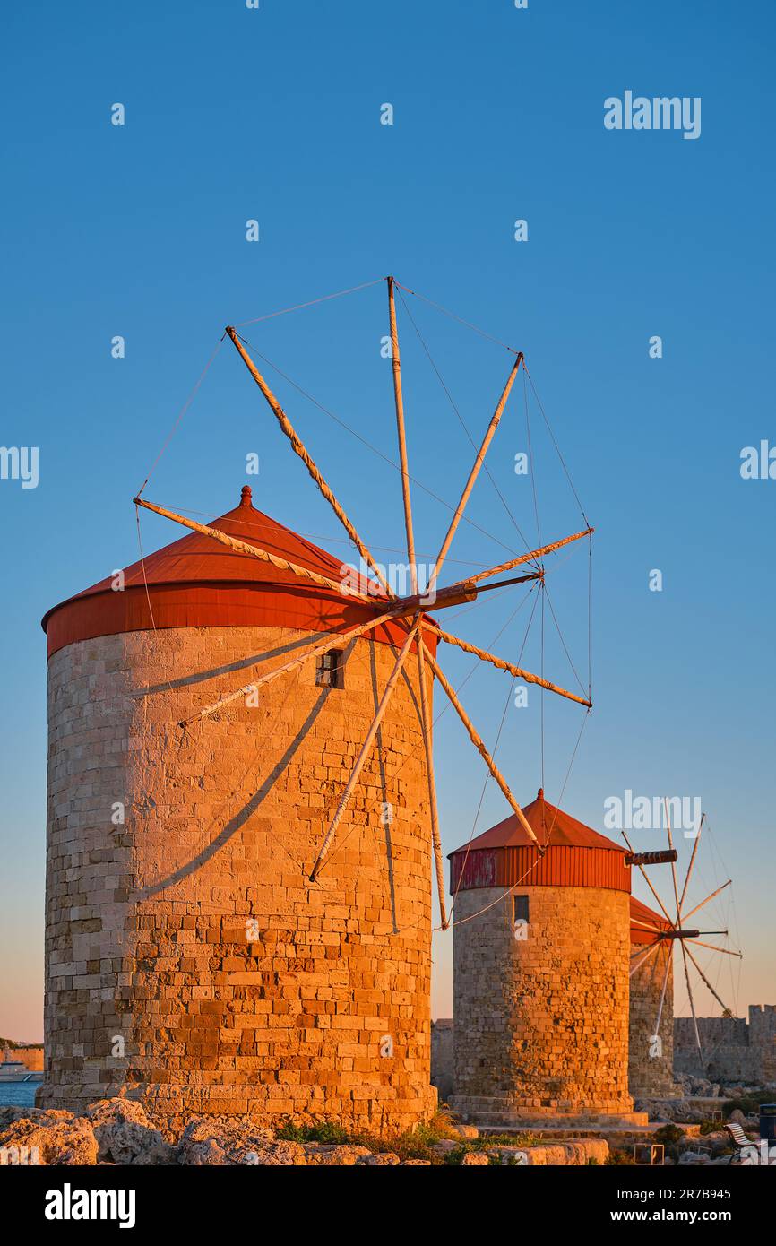 Telaio verticale sui vecchi mulini a vento sulla baia durante il tramonto, nella città di Rodi sull'isola di Rodi dell'isola dell'arcipelago Dodecaneso Foto Stock