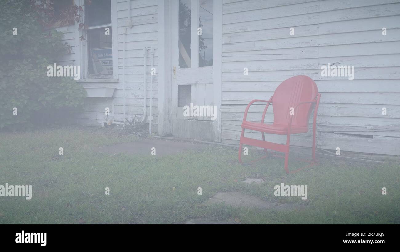 Sedia in metallo vintage rosso brillante su un vecchio capannone in legno bianco Foto Stock