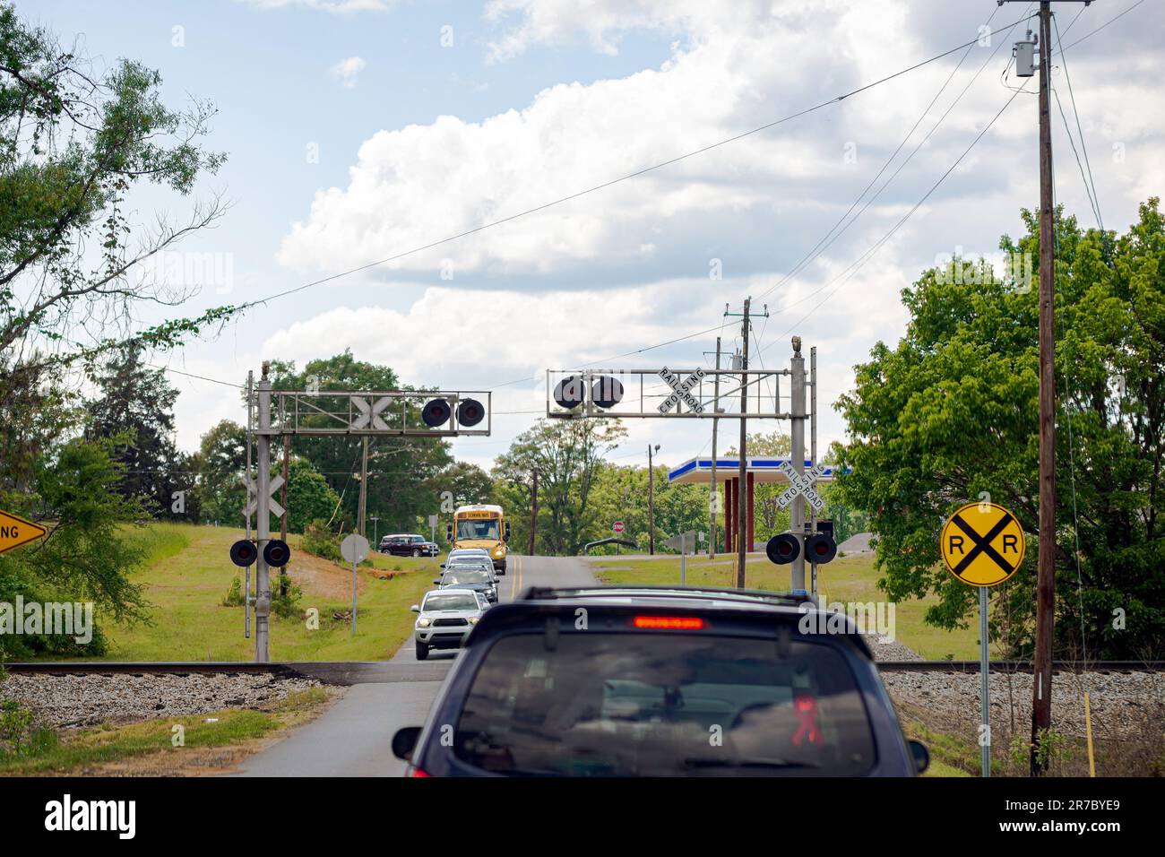 Una linea di veicoli aspetta ad un incrocio ferroviario senza un cancello di passaggio per il treno che ha appena superato. Foto Stock