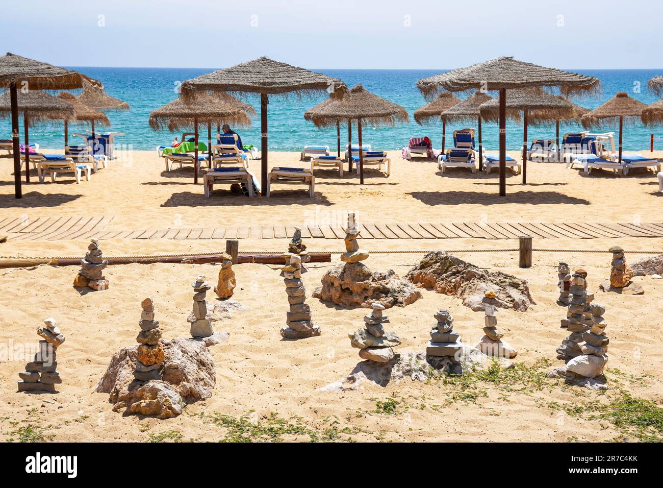 Praia de Quarteira, spiaggia e mare di Quarteira, Algarve, Portogallo, con lettini e ombrelloni e pali di pietra da meditazione Foto Stock