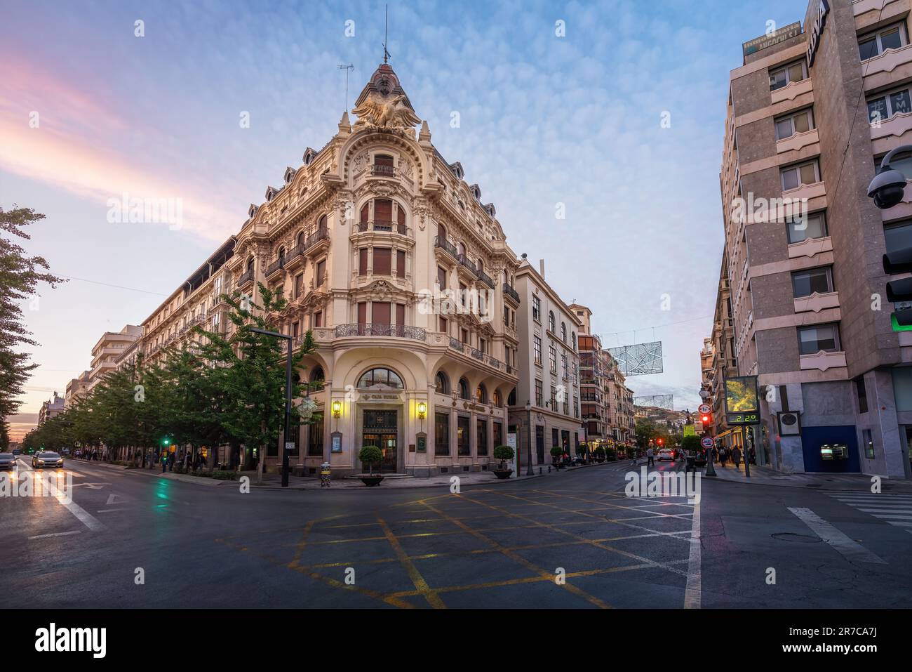 Edificio Banco Central Building e Gran Via de Colon Street al tramonto - Granada, Andalusia, Spagna Foto Stock