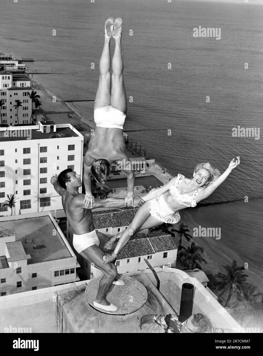Miami Beach, Florida: 15 novembre 1951 il trio Wayne-Marlin prova in cima al camino del Lord Tarleton Hotel. George Wayne Long tiene Glen Marlin Sundby e sua sorella Dolores senza sforzo apparente venti storie sopra il terreno. Foto Stock