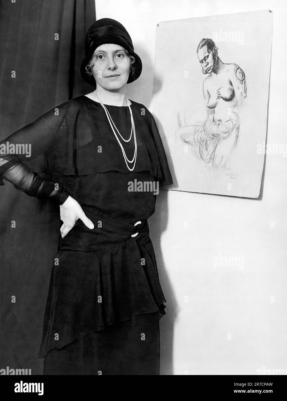 New York, New York: c. 1929 l'artista americana Caroline Mytinger, dopo aver fatto ritorno a casa da quattro anni di pittura nelle Isole del Mare del Sud, si trova accanto a uno dei suoi schizzi di un debutante nativo. I suoi dipinti saranno esposti nella Sala delle Filippine dell'American Museum of Natural History. Foto Stock