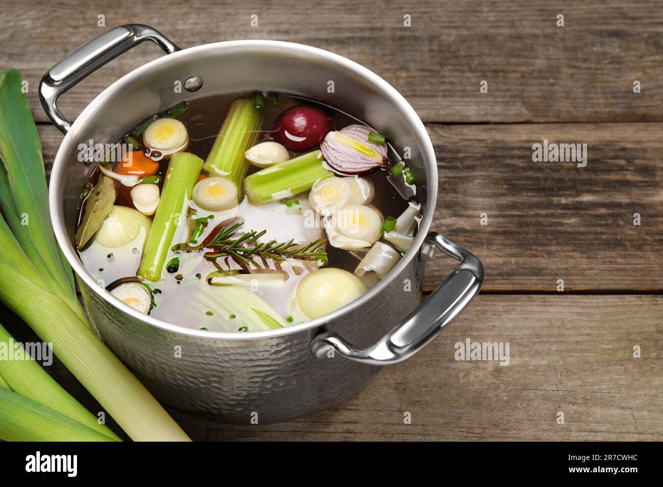 Ingredienti diversi per cucinare gustoso bouillon in pentola e sedano su tavolo di legno, spazio per il testo Foto Stock