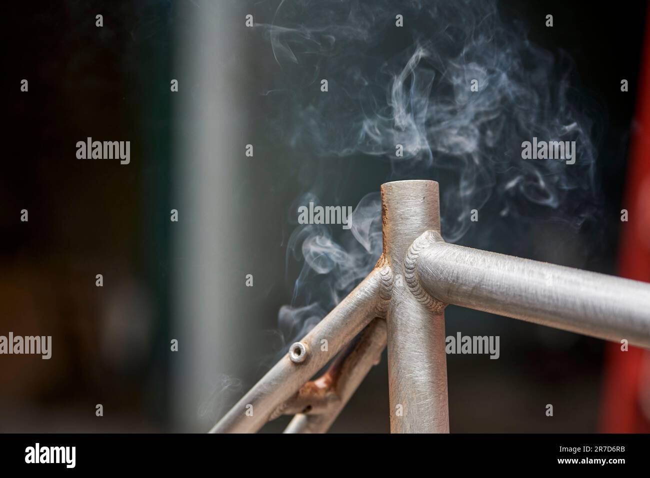 Fumo di metallo, lavori di ristrutturazione manuale della bicicletta, processo di rimozione della vernice utilizzando un fuoco a torcia per cambiare il colore del telaio della bicicletta. Vista ravvicinata, nessuna persona. Foto Stock