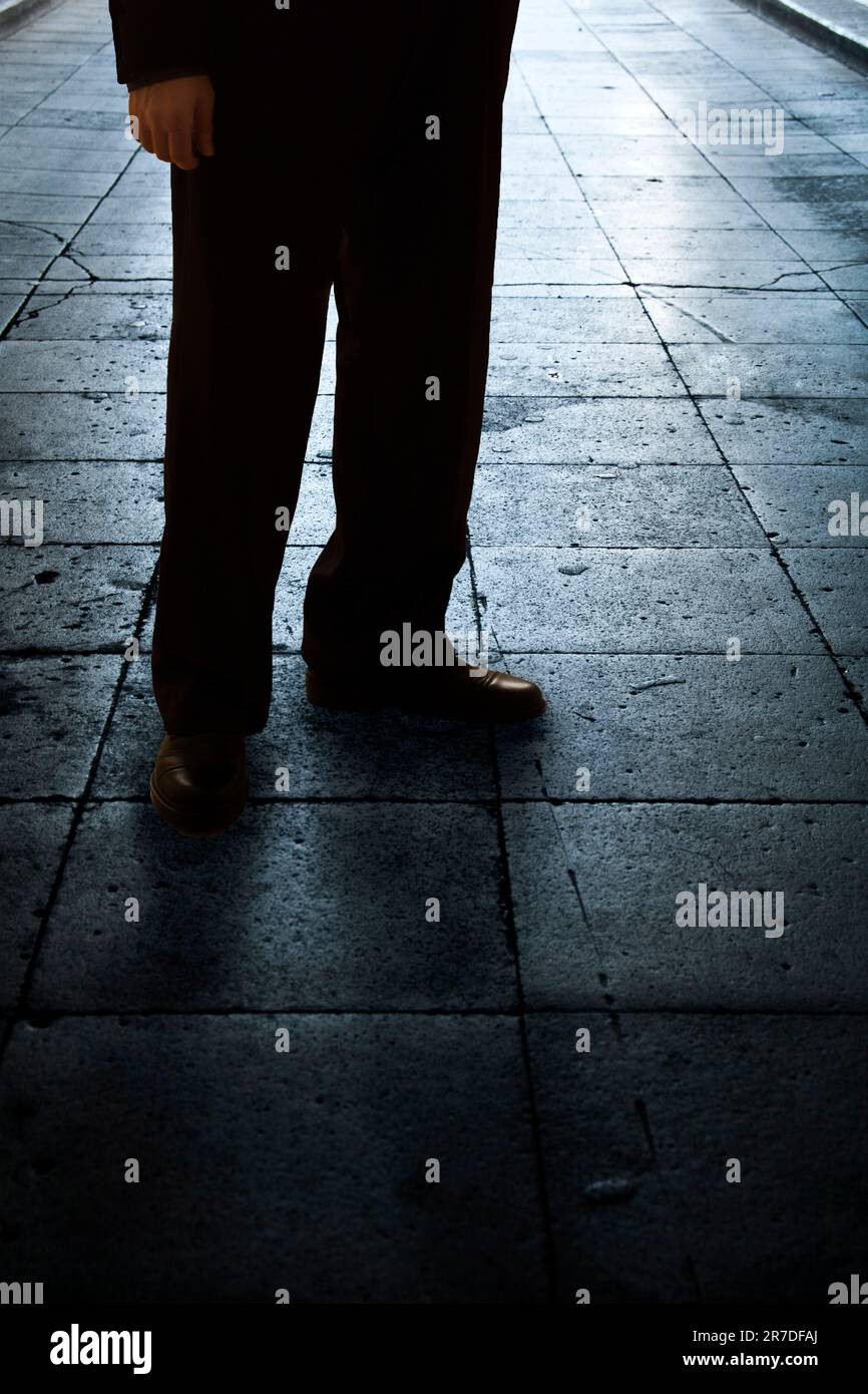 gambe e scarpe di un misterioso uomo in piedi per strada Foto Stock