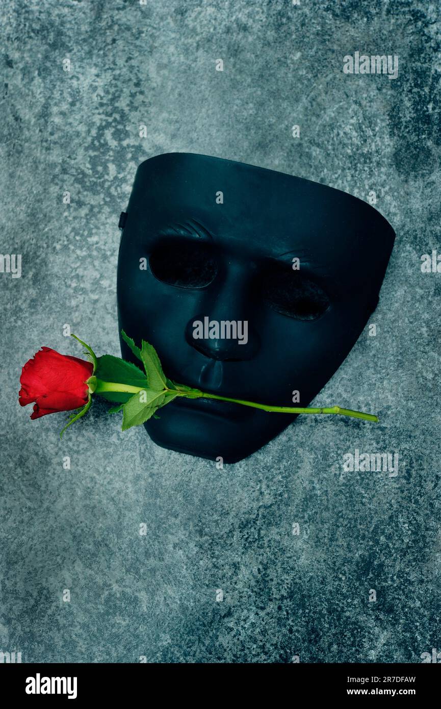 maschera nera con rosa rossa in bocca Foto Stock