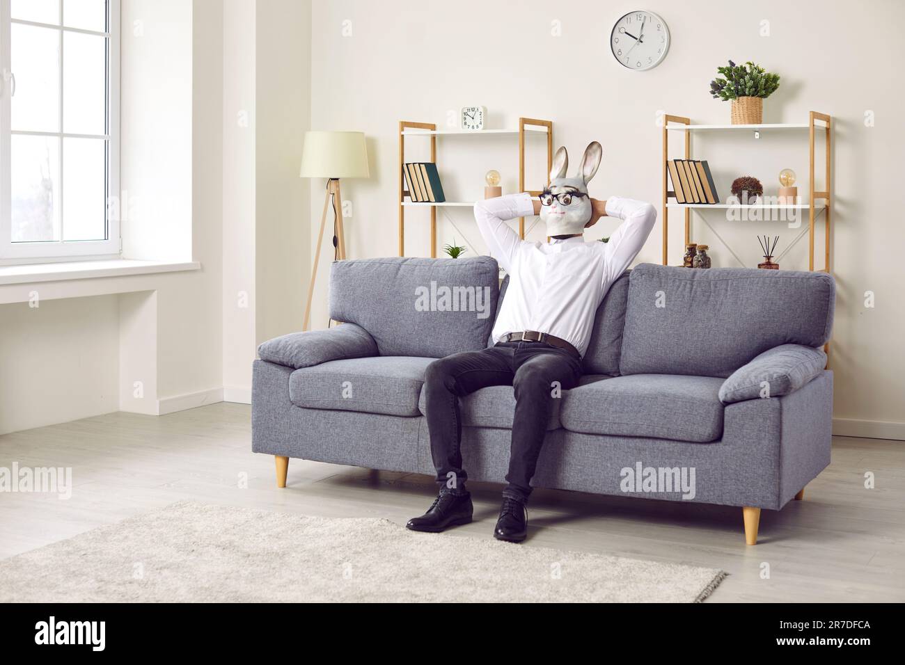 Uomo di coniglio d'affari che si gode fine settimana senza lavoro, seduto sul divano a casa, e rilassante Foto Stock