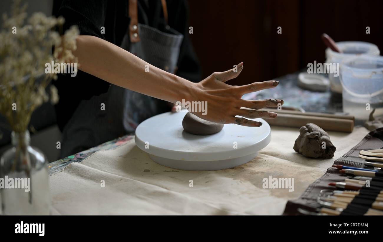 Immagine ravvicinata di un maestro vasaio maschio che impastava argilla grezza su una ruota di ceramica su un tavolo nel suo studio. artigianato, artigianato, scultura Foto Stock