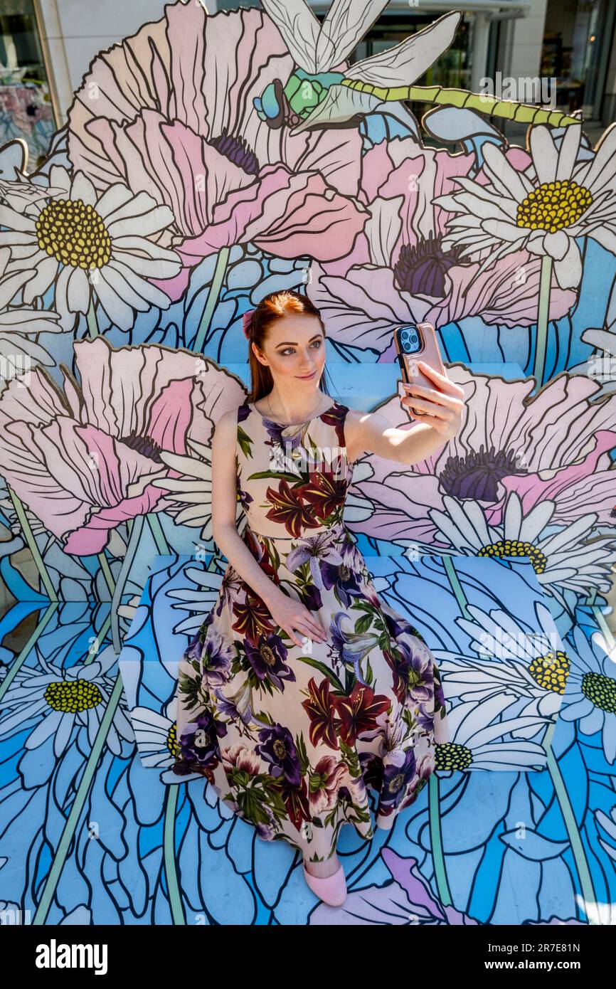 Londra, Regno Unito. 15 giugno 2023. Una donna prende un selfie con gli artisti Baker & Borowski's opera 'Graphic Rewilding Flower Clouds' in Duke of York Square in un'anteprima dell'annuale Public Art Trail di Kensington and Chelsea Art Week (KCAW), che presenta sculture, installazioni e murales di livello mondiale esposti in tutto il quartiere dal 22 giugno al 31 agosto. Credit: Stephen Chung / Alamy Live News Foto Stock