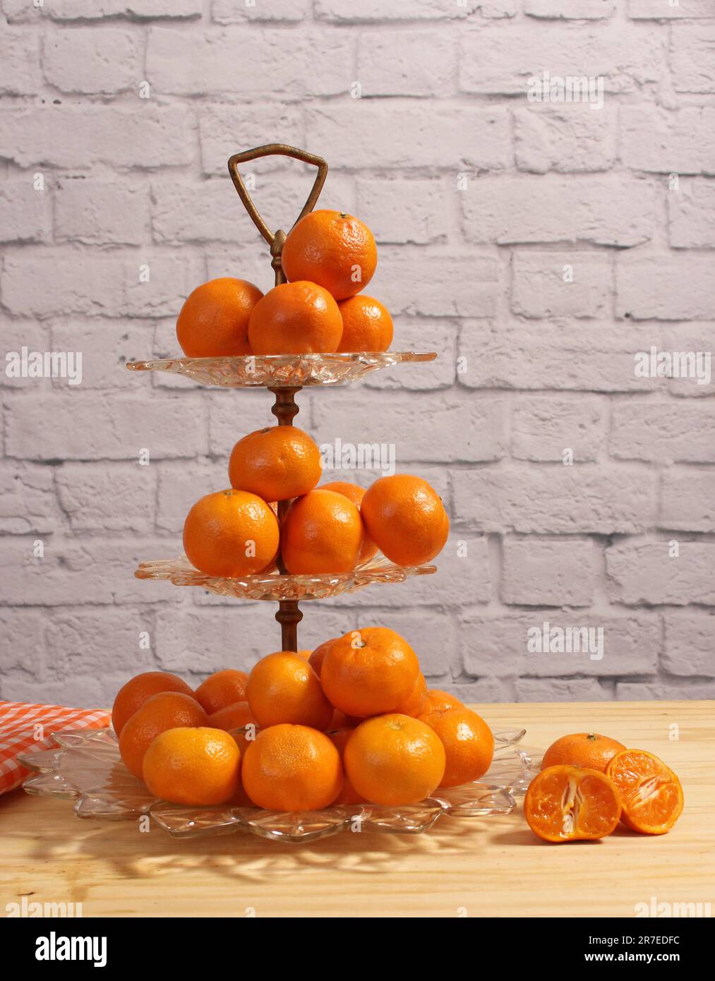 Piatto di cristallo antico con arance piccole. Dessert Display con parete di mattoni sullo sfondo Foto Stock