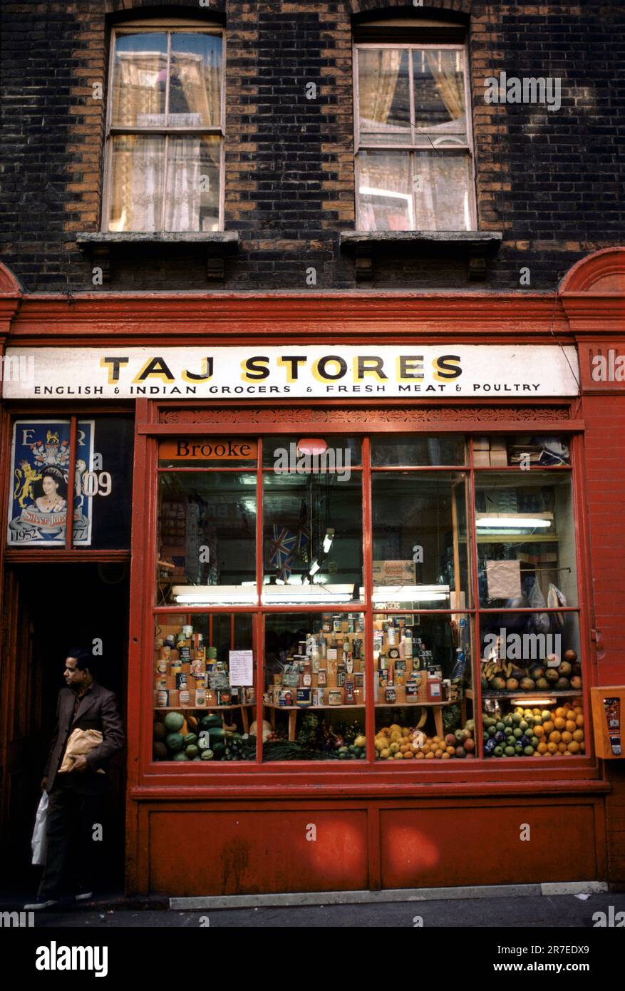Celebrazioni del Giubileo d'Argento della Regina Elisabetta II 1977. Un negozio di alimentari inglese e indiano, un negozio di alimentari multietnico a Brick Lane, East London. Il poster nella finestra sopra la porta è per il Queens Silver Jubilee. Tower Hamlets, Londra, Inghilterra circa giugno 1977. Foto Stock