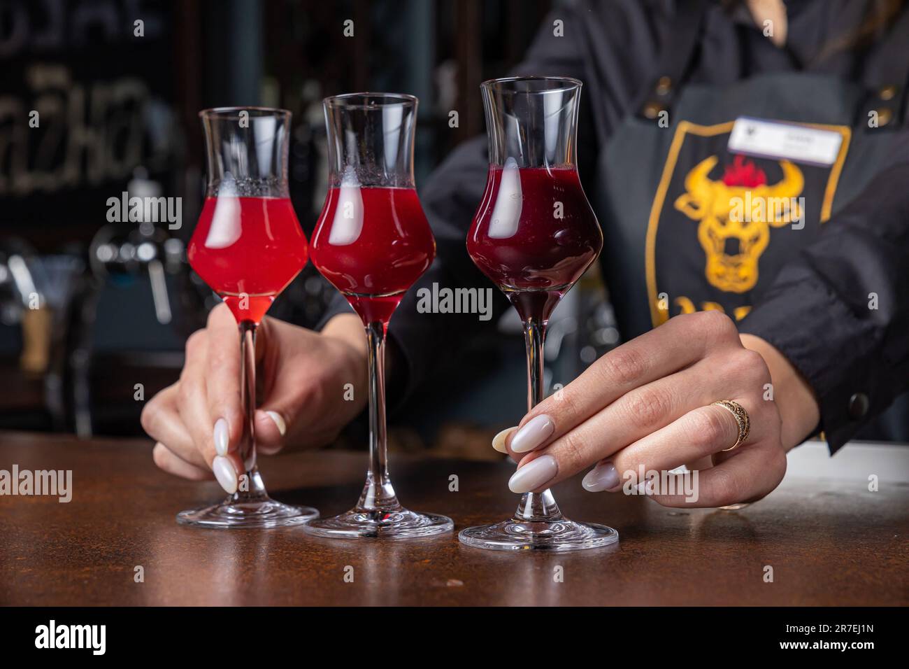 Un barista professionista che organizza cocktail rossi su un banco bar Foto Stock