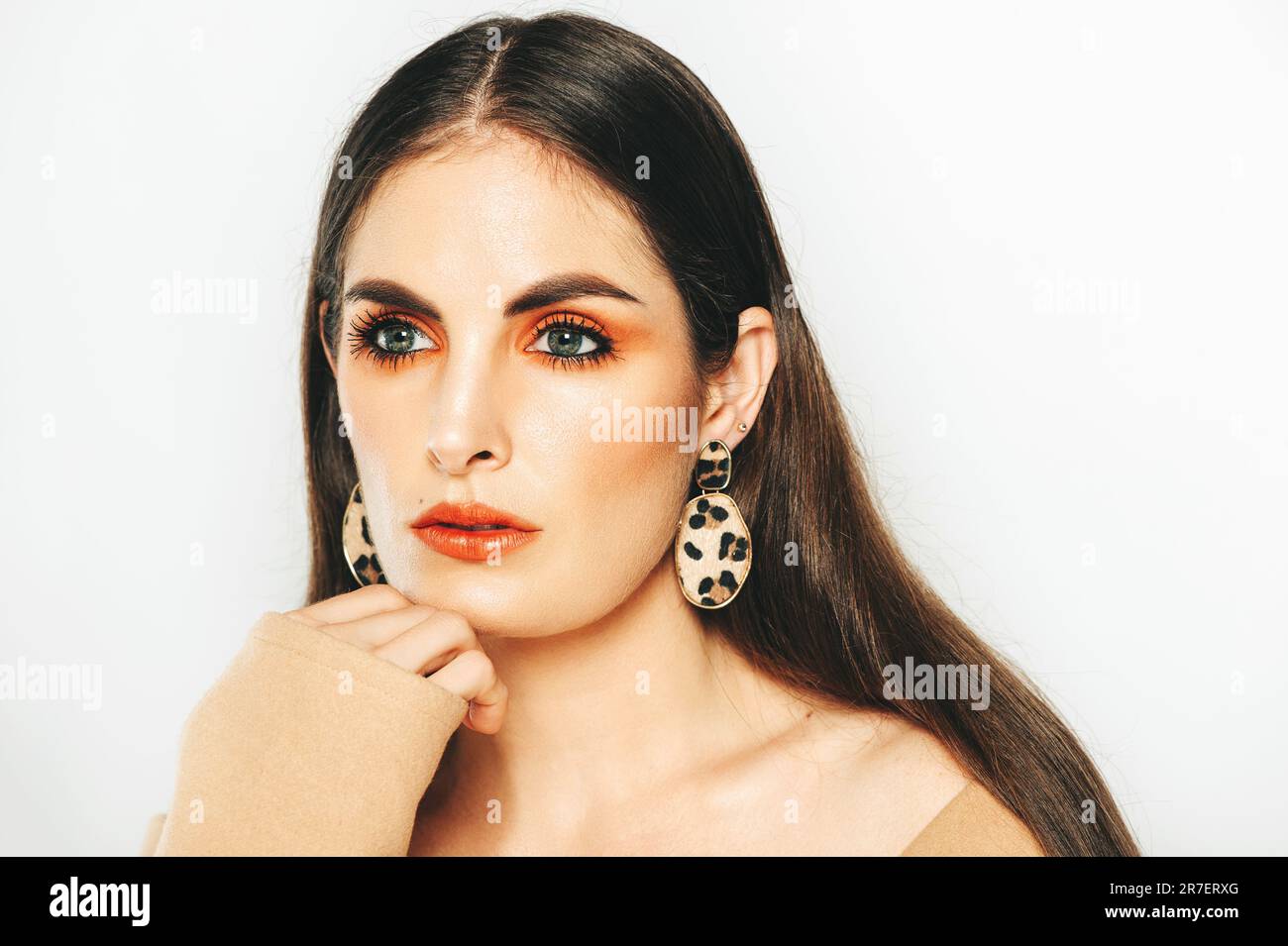 Studio shot di bella giovane donna con capelli scuri e occhi blu, con vestito marrone a spalla aperta Foto Stock